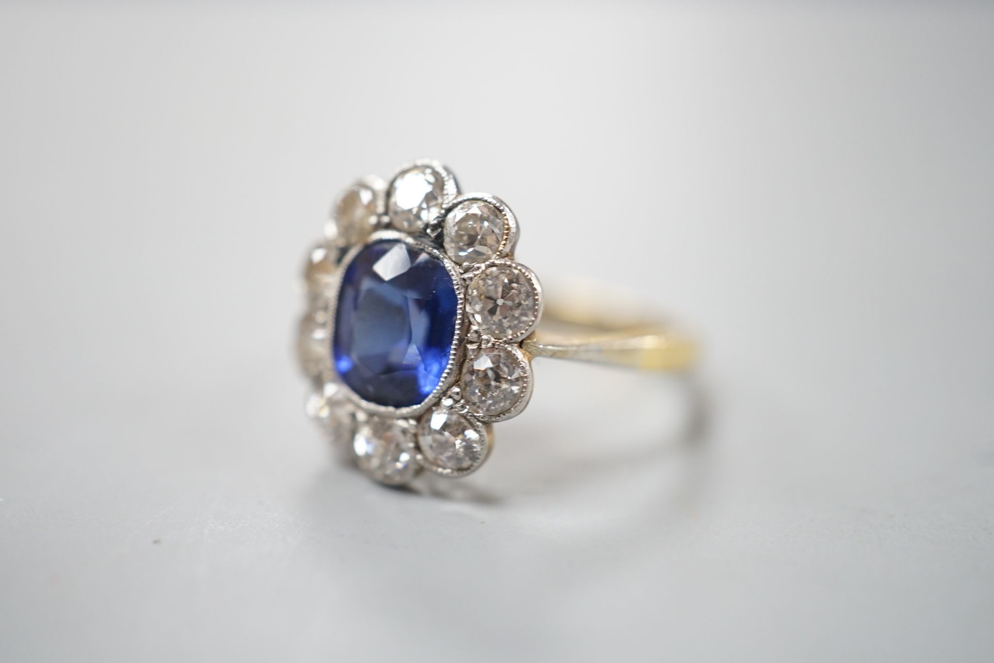 An 18ct gold and platinum, synthetic sapphire and diamond set oval cluster ring